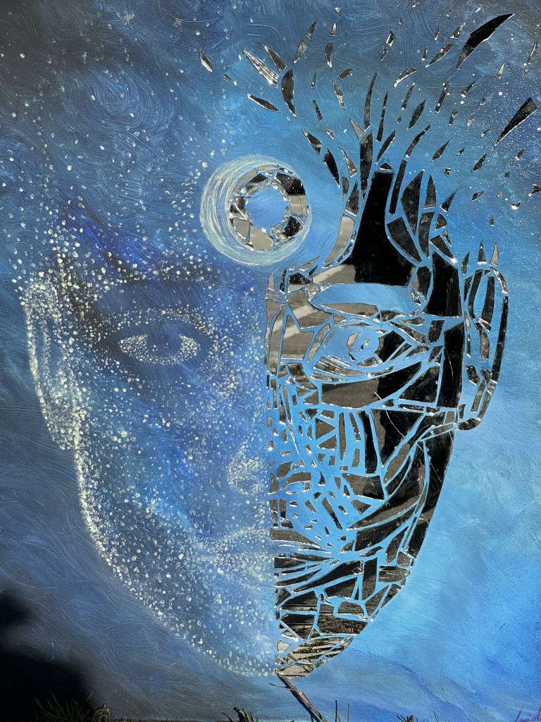 Artwork of a mirrored face on a blue backgound by Lucius N. Amberg
